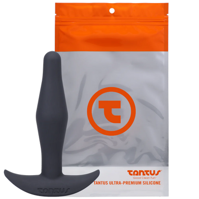 Tantus Little Flirt butt plug in black silicone with curved base displayed in front of branded resealable pouch packaging.