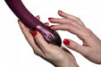 Hands with red nail polish holding and adjusting plum-colored Hot Octopuss Kurve G-spot vibrator with control buttons visible.
