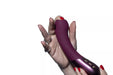 Hand holding a plum-colored Hot Octopuss Kurve G-spot vibrator with ergonomic shape and control buttons visible.