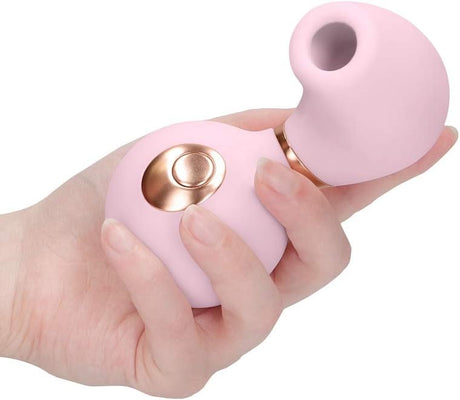 Hand holding a pink, ergonomic clitoral vibrator with a rose gold control button and soft silicone finish.