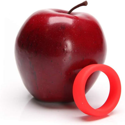 Bright red soft silicone c-ring displayed next to a shiny red apple on a white background.