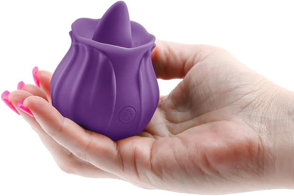 Hand holding a compact purple rosebud-shaped clitoral stimulator made of soft silicone.