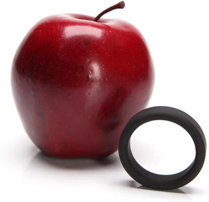 Black soft silicone c-ring displayed next to a red apple for size comparison on a white background.