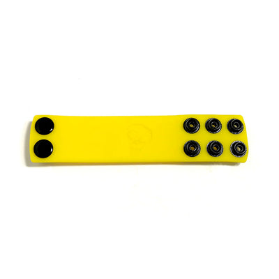Yellow silicone ball stretcher strap with multiple black snap fasteners for adjustable sizing.