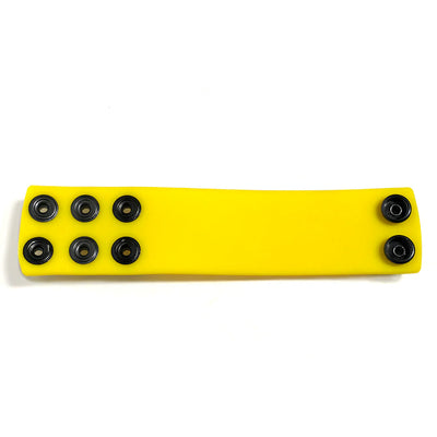 Yellow silicone ball stretcher strap with multiple black snap fasteners for adjustable sizing.