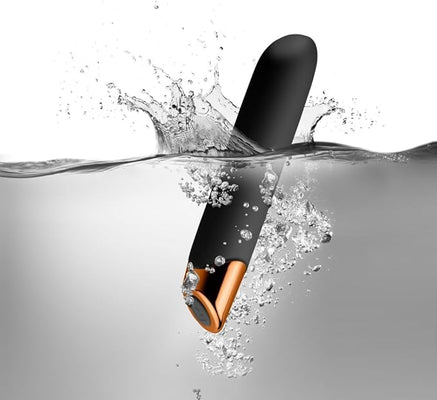 Black and rose gold waterproof vibrator submerged in water with splash and bubbles around it.