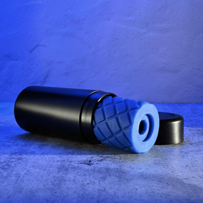 Black cylindrical case with a removable blue textured silicone stroker insert on a concrete surface with blue lighting.