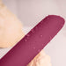 Close-up of burgundy waterproof vibrator with water droplets on smooth silicone surface.