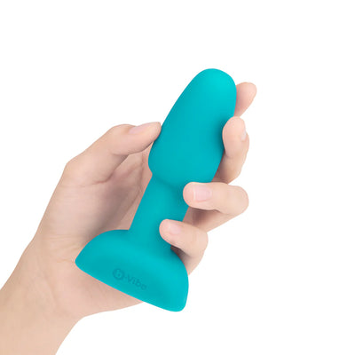 Hand holding a compact turquoise silicone B-Vibe Rimming Petite Plug designed for beginner anal play.