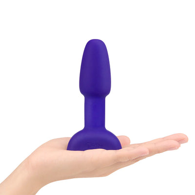 Compact purple silicone vibrating rimming plug held in an open hand, designed for beginner-friendly anal stimulation.