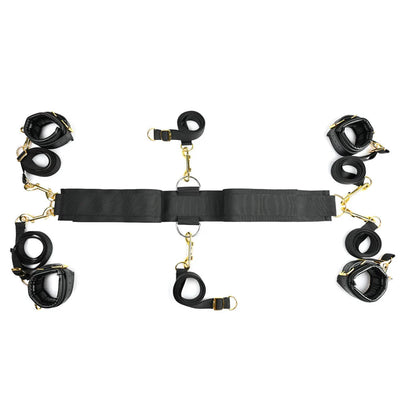 Special Edition under bed restraint set with six adjustable black straps, four faux leather cuffs, golden hardware, and a central connector strap.