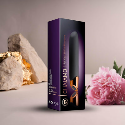 Chaiamo Burgundy vibrator packaging with black and rose gold design, displayed with natural stones and pink flower background.