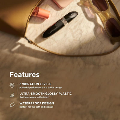 Compact black Lelo Mia 2 massager with glossy finish beside sunglasses and a purse on a marble surface.