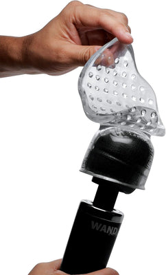 Hand holding a clear textured stroker attachment being placed on a black massage wand for male stimulation.