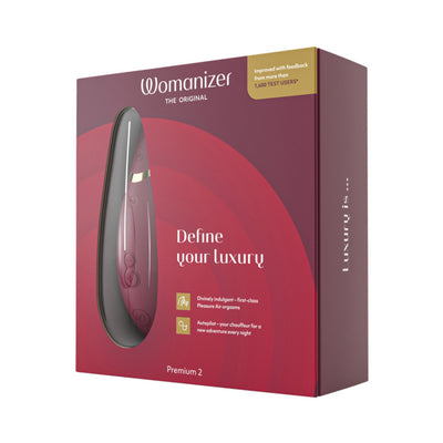 Womanizer Premium 2 clitoral stimulator in burgundy packaging with product image and luxury branding details.
