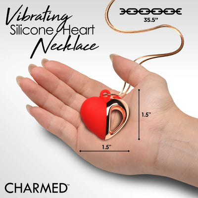 Hand holding a red and rose gold silicone heart necklace pendant with chain length and pendant size measurements shown.