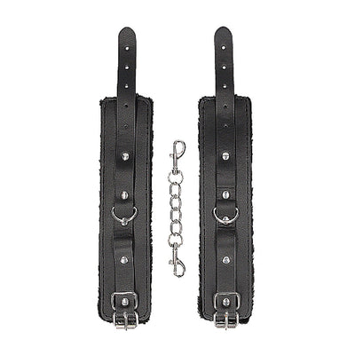 Black and white plush bonded leather hand cuffs with adjustable straps and metal chain connector on white background.