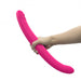 Hand holding a flexible, dual-ended pink silicone double-ended vibrator with textured tips.