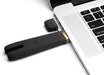 Black Crave Duet Flex dual-tip vibrator plugged into a laptop USB port for charging with attached protective cap.