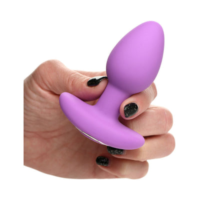 Hand holding a vibrant violet silicone butt plug with a wide base and smooth, tapered design.