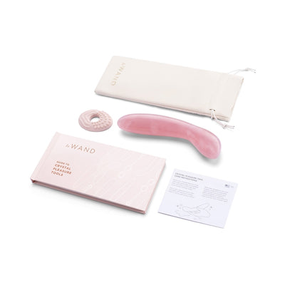 Le Wand Crystal G-wand in rose quartz with textured silicone sleeve, guidebook, care instructions, and storage pouch on white background.