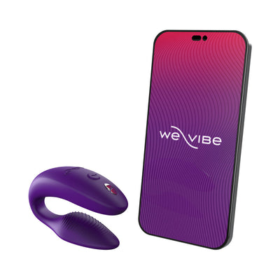 Purple We-Vibe Sync couples vibrator next to smartphone displaying We-Vibe app interface on white background.