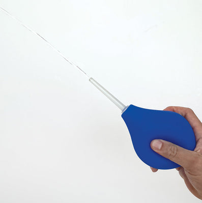 Hand holding a blue 8 oz. silicone bulb douche kit with water spraying from the translucent nozzle.