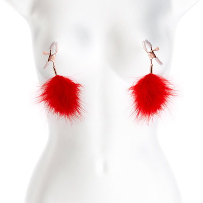 Rose gold adjustable nipple clamps with soft silicone tips and bright red feather accents on a white mannequin torso.