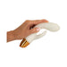Hand holding a white silicone rabbit vibrator with gold base and textured stimulator on a white background.