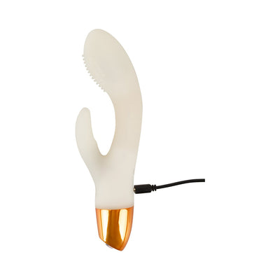 White glow-in-the-dark rabbit vibrator with textured tip and gold base, shown with USB charging cable connected.