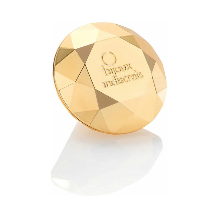 Gold faceted diamond-shaped clitoral vibrator with Bijoux Indiscrets logo on a white reflective surface.