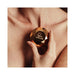 Hand holding a rose gold faceted diamond-shaped Bijoux Indiscrets Twenty One vibrator against bare skin background.