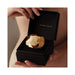 Hand holding an open black box containing a gold faceted Bijoux Indiscrets Twenty One Vibrating Diamond.