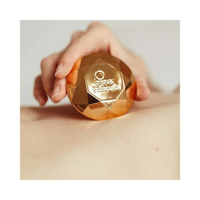 Hand holding a gold faceted Bijoux Indiscrets Twenty One Vibrating Diamond on skin, showcasing its compact design.