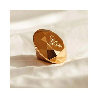 Gold faceted diamond-shaped clitoral vibrator by Bijoux Indiscrets resting on soft fabric background.