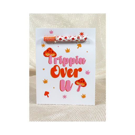 Trippin Over U greeting card with colorful mushroom and leaf designs, featuring a matching patterned one hitter attached.