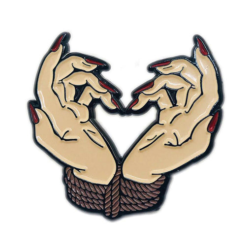 Enamel pin of two hands with red nails tied together by rope forming a heart shape.