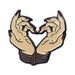 Enamel pin of two hands with red nails tied together by rope forming a heart shape.