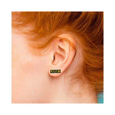 Close-up of ear wearing gold glitter stud earrings with bold text design.