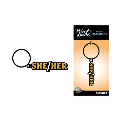 Black and gold enamel keychain with "She/Her" text on a black ring, displayed on Wood Rocket branded backing card.
