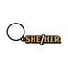 Black and gold enamel keychain with glittery "She/Her" text and a black keyring attached.