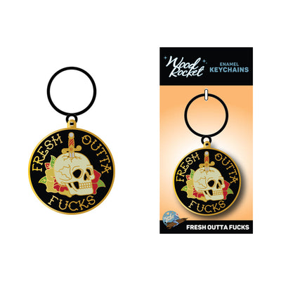 Enamel keychain featuring a skull with a dagger and floral design, text reads Fresh Outta Fucks, black and gold colors.