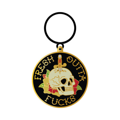 Round enamel keychain featuring a skull with a dagger and floral design, text "Fresh Outta Fucks" on black background.