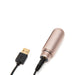 Rose gold cylindrical rechargeable battery base with USB charging cable connected on white background