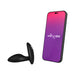 Black silicone vibrating anal plug next to smartphone displaying We-Vibe app interface on white background.