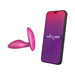 Pink silicone vibrating anal plug next to smartphone displaying We-Vibe app interface for remote control.