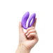 Hand holding a compact purple We-Vibe Sync O couples vibrator with a flexible O-shaped design.