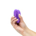 Hand holding a compact purple silicone We-Vibe Sync O couples vibrator against a white background.