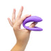 Hand holding a purple flexible We-Vibe Sync O couples vibrator against a white background.