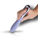 Hand holding Niya 3 Precision Point Massager in cornflower blue with ergonomic loop handle and smooth silicone tip.